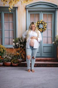 Maternity photoshoot with a floral backdrop. Maternity shoot where mom is standing and holding her belly. San Antonio Maternity photographer. San Antonio Photographer