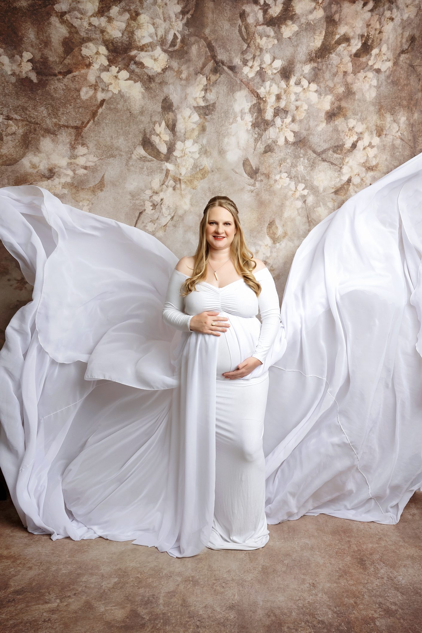 Maternity photoshoot in studio. Pregnant mom posing for camera. Photoshoot in san antonio. White flowy maternity gown.