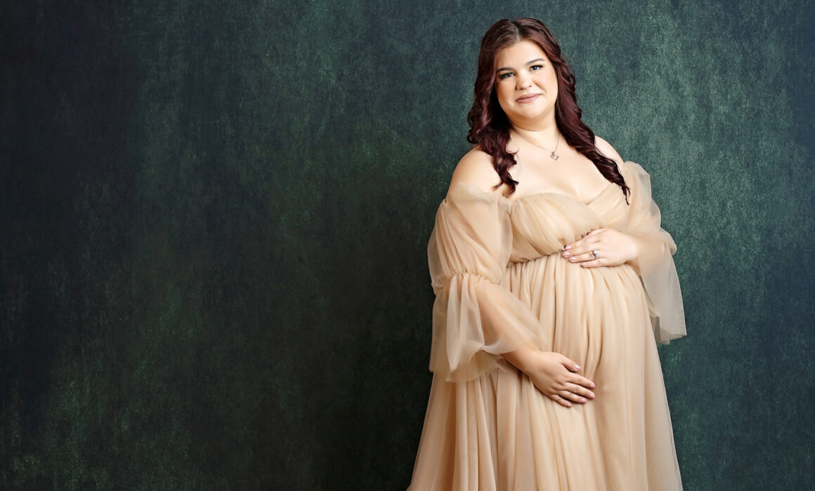 San Antonio maternity photographer, Maternity photo in beige gown with green background in San Antonio studio