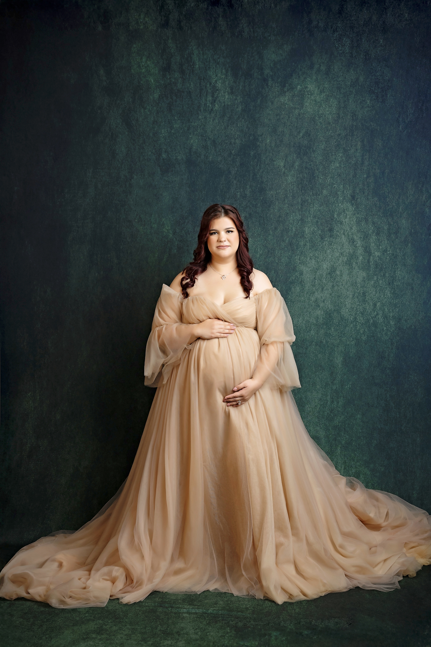 Maternity photo in beige gown with green background in San Antonio studio