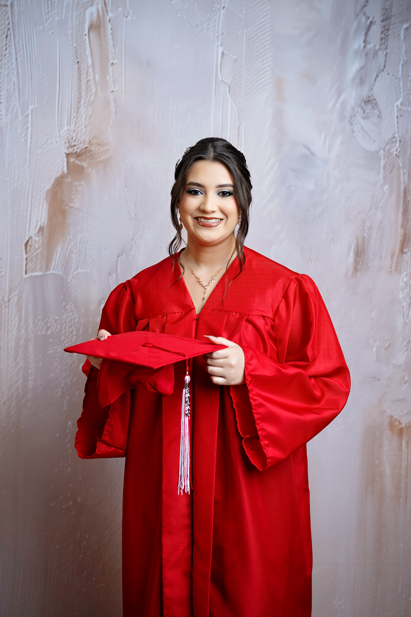 san antonio senior photographer san antonio senior poses for a studio photoshoot. wearing red cap and gown.