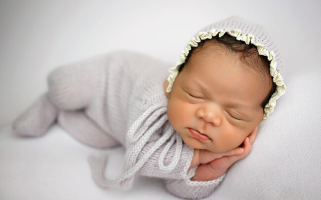 Sleeping newborn girl wearing a soft purple outfit during San Antonio newborn photography session