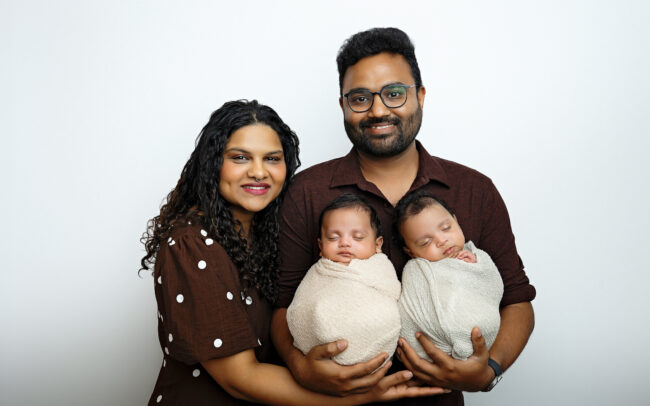 Parents holding their sleeping newborn twins during a studio newborn session in San Antonio