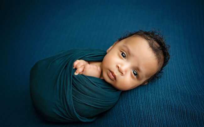 Awake newborn baby wrapped in teal during a San Antonio newborn photo session