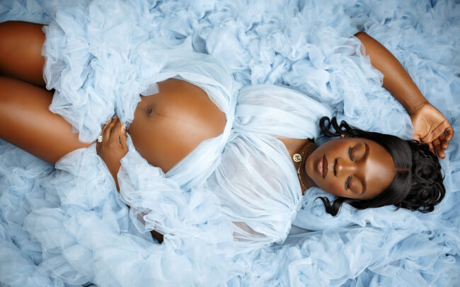 San Antonio maternity photographer studio session with expecting mother in blue tulle gown and spouse on blue backdrop