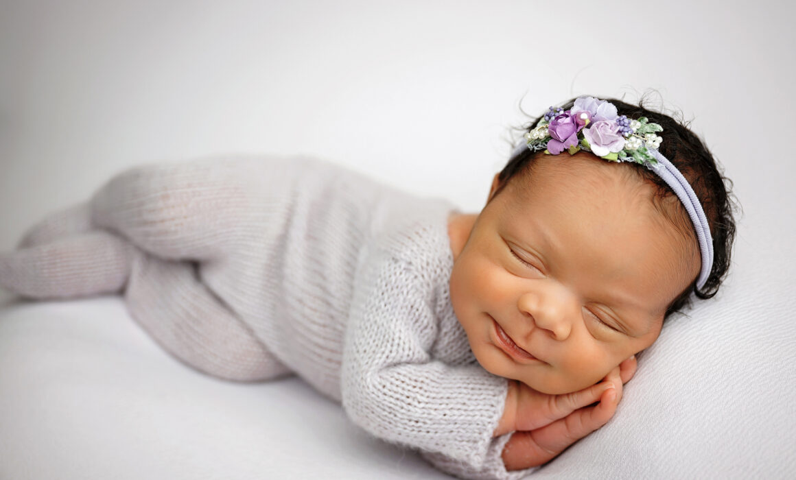 Sleeping baby girl in gray newborn outfit and lavender floral headband