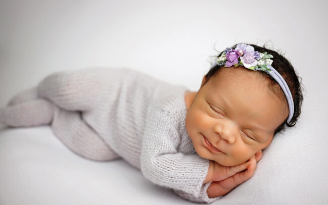 Sleeping baby girl in gray newborn outfit and lavender floral headband