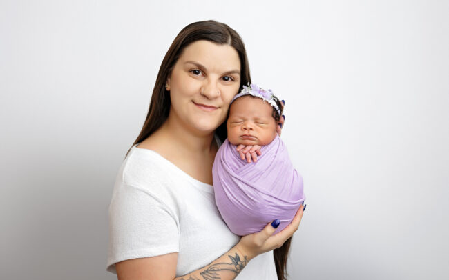 Mother holding newborn daughter wrapped in lavender during San Antonio newborn photography session