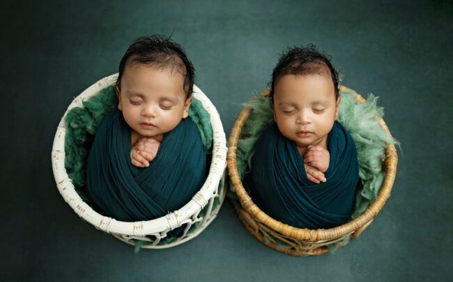 Newborn twins wrapped in teal and posed separately in coordinating baskets