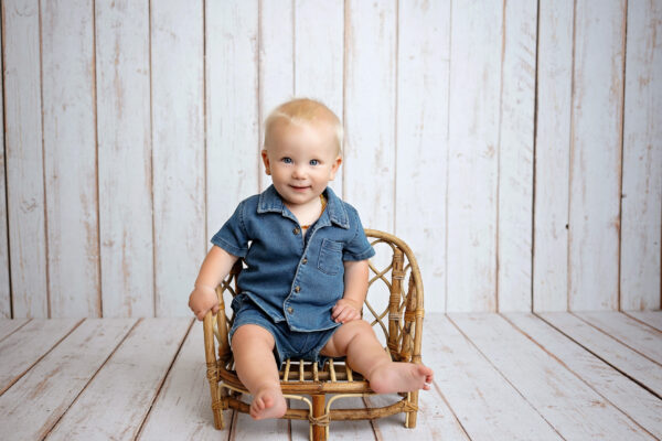 Smiling baby sitting in a wicker chair during a San Antonio baby milestone photography session