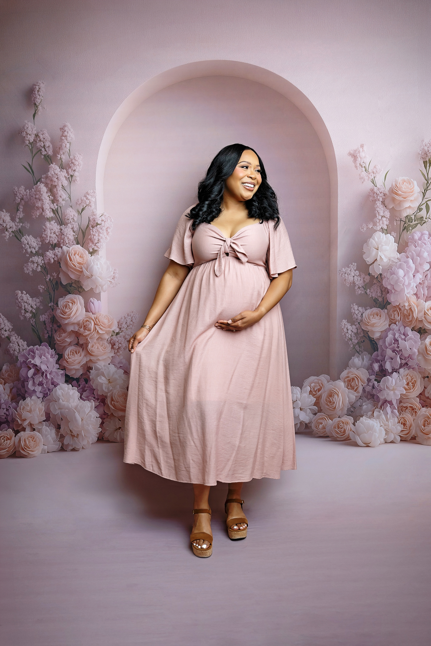elegant-san-antonio-maternity-photographer Expecting mother smiling in a flowing blush pink dress during an elegant studio maternity session in San Antonio.