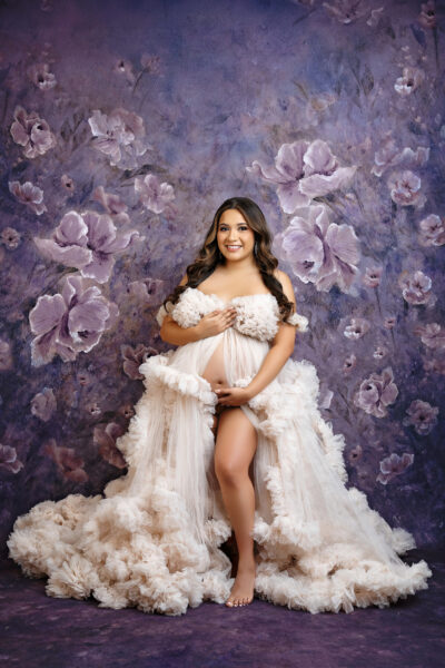 Ivory floral gown:
Luxury maternity photography in San Antonio featuring ivory ruffled designer gown and floral backdrop