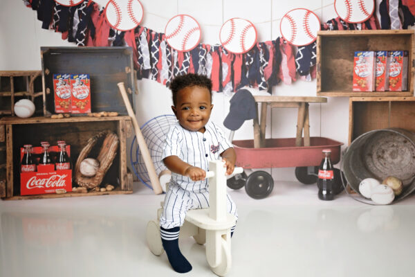 Baby standing with a wooden push toy during an 8-month baseball milestone photo session