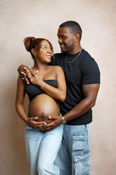 Pregnant mother and partner smiling at each other during a San Antonio maternity photography session.