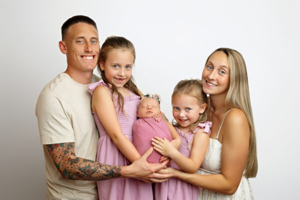 Newborn baby girl posed with her parents and sisters in a San Antonio photography studio