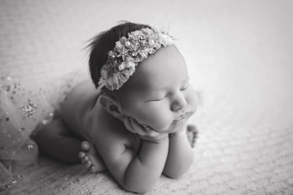 Newborn baby girl froggy pose with delicate headband