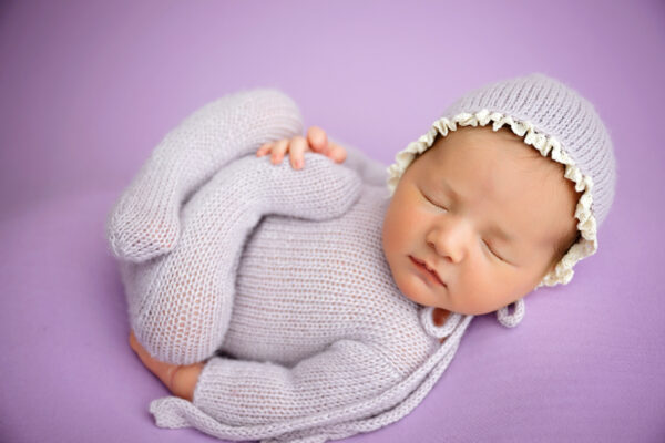 Baby girl posed in lavender knit outfit and bonnet