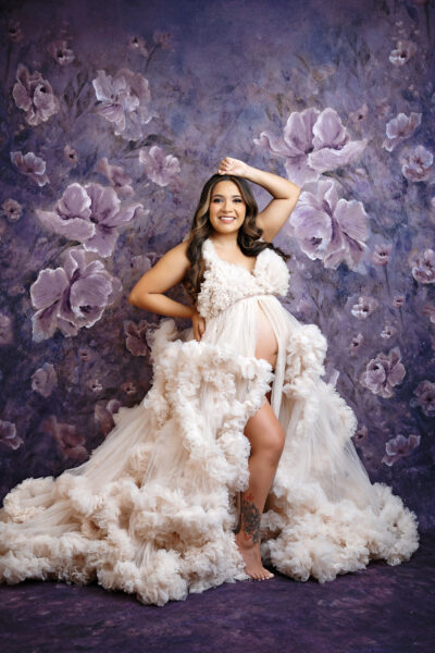 Ivory floral gown:
Luxury maternity photography in San Antonio featuring ivory ruffled designer gown and floral backdrop