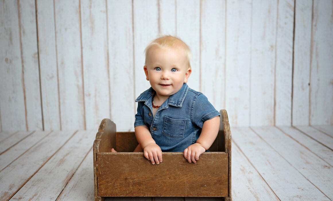 Baby smiling in a vintage wooden bed during a studio milestone session in San Antonio