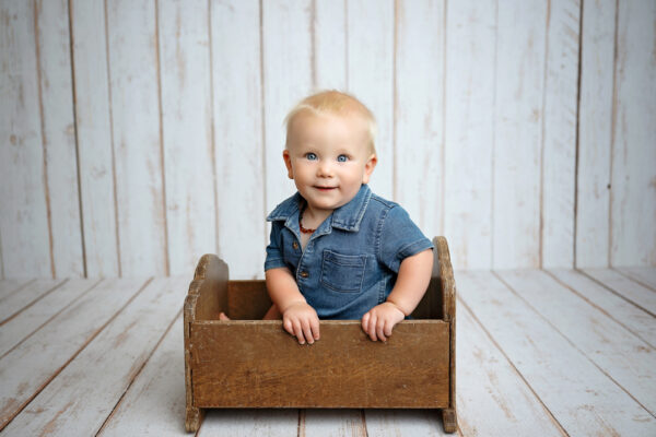 Baby smiling in a vintage wooden bed during a studio milestone session in San Antonio