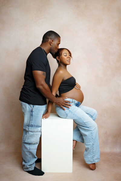 Expecting couple seated together for modern studio maternity portraits in San Antonio.