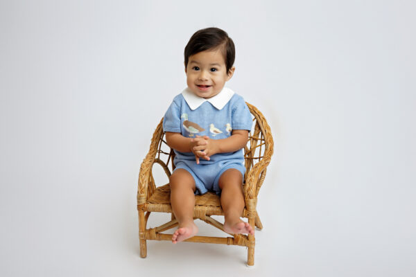 Laughing one-year-old boy enjoying his birthday cake during a San Antonio cake smash photography session.