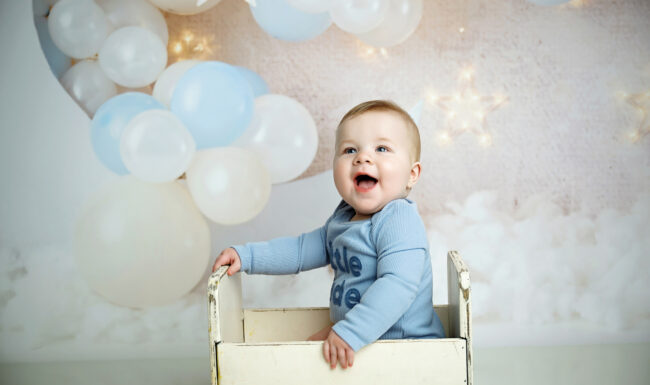 Smiling six month old baby wearing a blue Little Dude outfit during a milestone photography session in San Antonio.