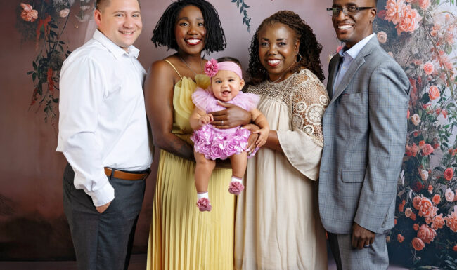 Extended family portrait with grandparents, daughter, son-in-law and baby girl against a romantic floral backdrop