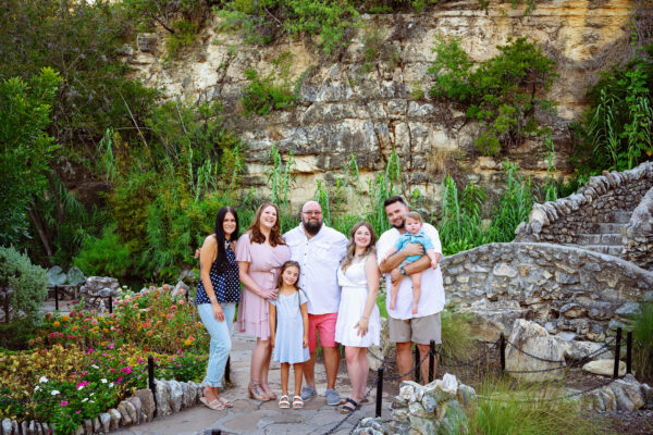 Large family posing together on a stone bridge surrounded by lush gardens in San Antonio