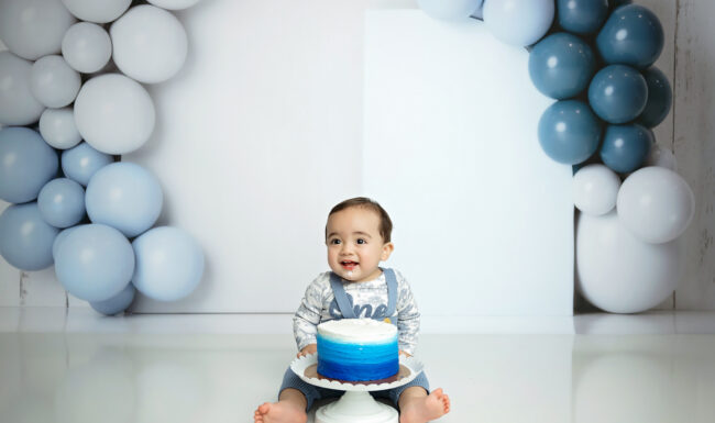 One-year-old baby boy with a blue ombre birthday cake during a San Antonio cake smash session