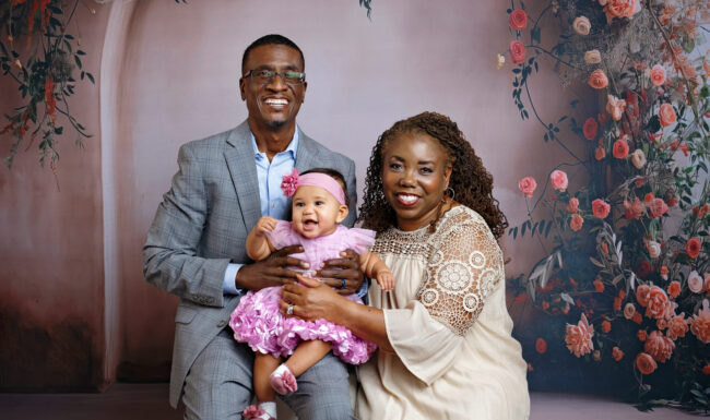 Smiling grandparents holding their baby granddaughter during an heirloom family photography session