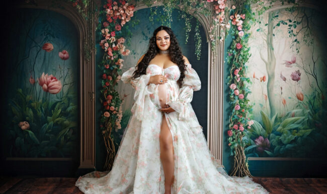 Studio maternity portrait of pregnant mom holding her baby bump in a floral client closet gown