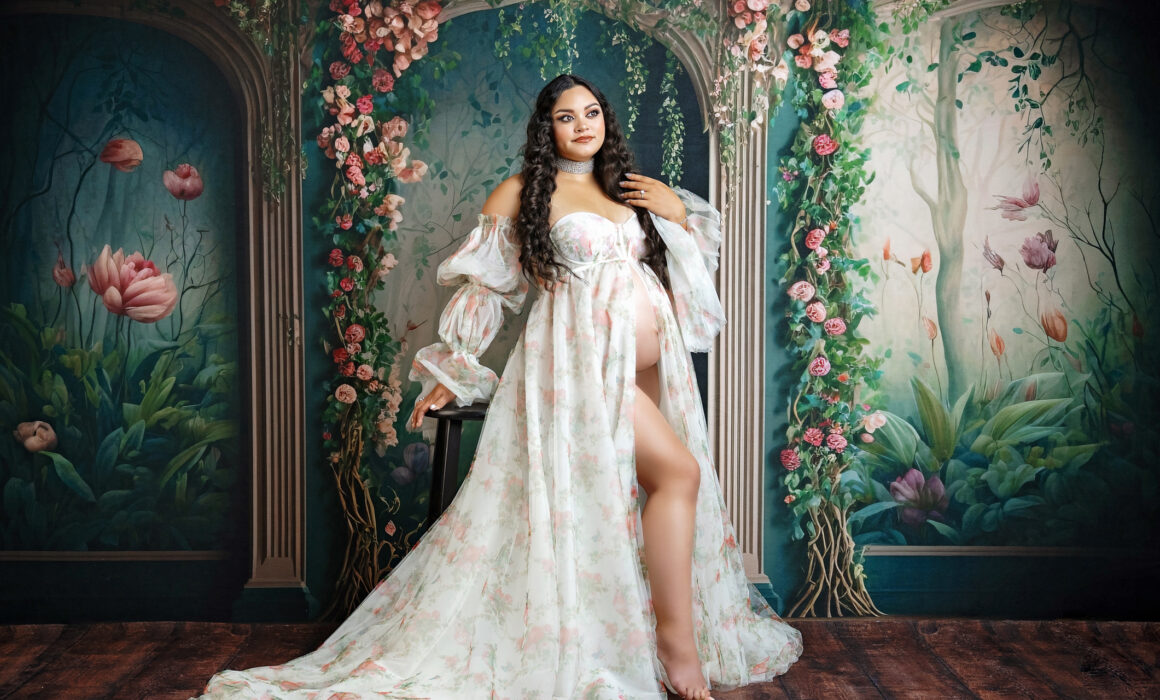 San Antonio maternity photography featuring an expecting mother in a floral gown with a garden-inspired backdrop