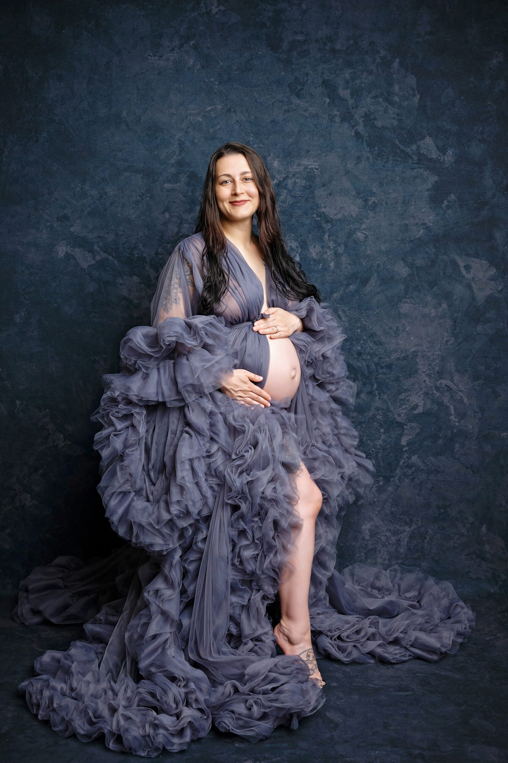 maternity photoshoot with mom posing in grey gown.
