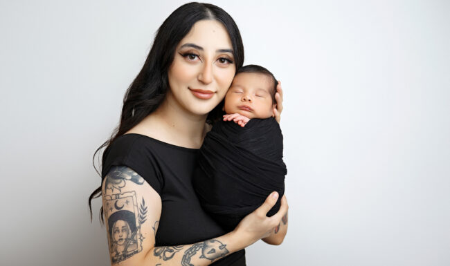 Mother holding her newborn baby wrapped in black during a San Antonio newborn photography session.