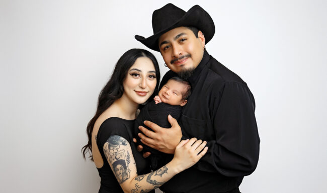 Mom and dad holding their newborn baby together during a family newborn portrait in a San Antonio photography studio.
