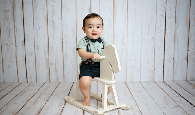 One-year-old boy sitting on a white rocking horse during his San Antonio milestone photography session