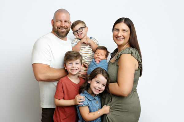Family of six cuddling their newborn baby boy during a San Antonio studio newborn session.