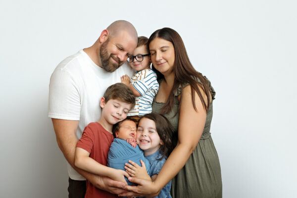 Mom and dad holding their sleeping newborn baby boy in a soft studio portrait.