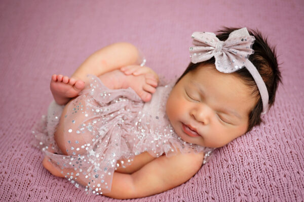 Overhead newborn portrait of baby girl wearing delicate pink dress