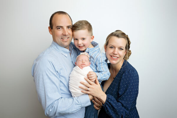 San Antonio family newborn portrait featuring proud parents and big brother holding their newest baby girl in the photography studio.
 Copy