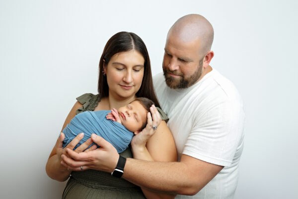 Parents holding their sleeping newborn baby boy during a studio newborn session in San Antonio.