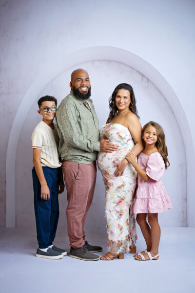 Family of four posing together in a photography studio while expecting their next baby